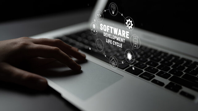 Hand Typing on Laptop with Holographic Icons Representing Software Development Life Cycle and Technology Concepts in Dark Setting Quark.