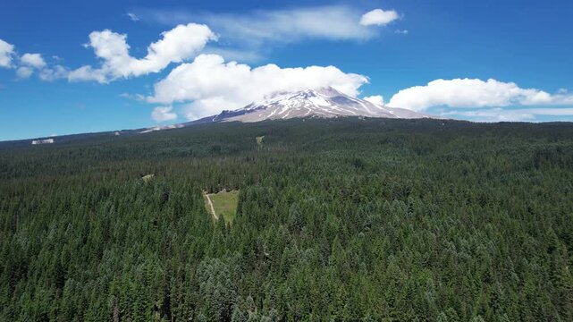 Right to Left  Aerial shot of Mount Hood Oregon in the bright summertime with clouds around mountain.