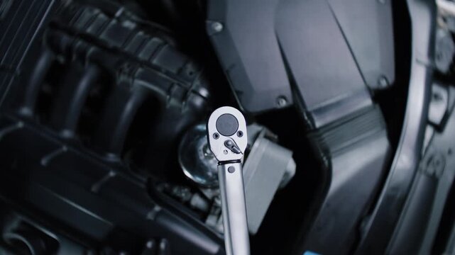 The camera is attached to a torque wrench and films the work being carried out under the bonnet of a car at a garage whilst it is being repaired 