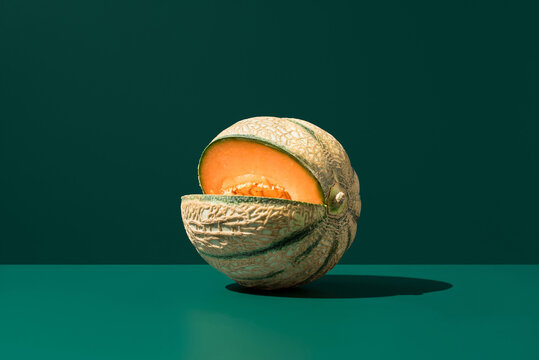 Minimal cantaloupe melon on green background with shadow