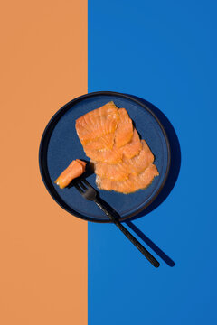 Smoked salmon slice on blue plate with fork, top view