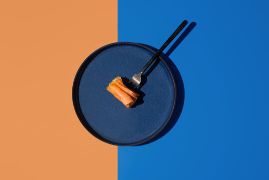 Minimal smoked salmon bite on blue plate, split background