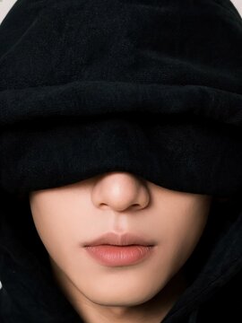 Mysterious person with eyes covered by black cloth fabric isolated on dark background