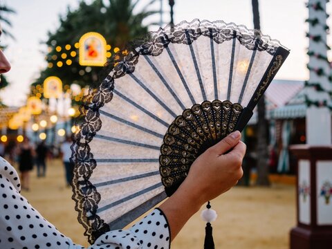 Woman holding a traditional Spanish hand fan at a festive street fair