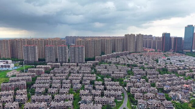 Aerial view of mixed residential district with dense villas and high-rise apartment buildings under cloudy sky
