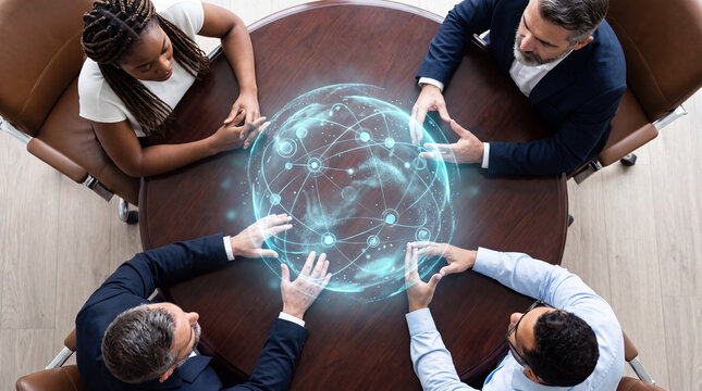 Colleagues reaching toward a glowing network sphere hologram on a table, overhead view