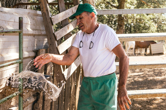 Veterinarian washing hands at farm gate near livestock pen