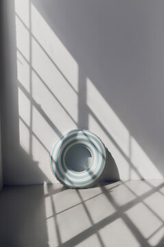 Striped pool float in sunlight by the wall