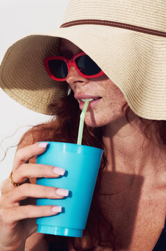Woman enjoying summer drink poolside with straw hat