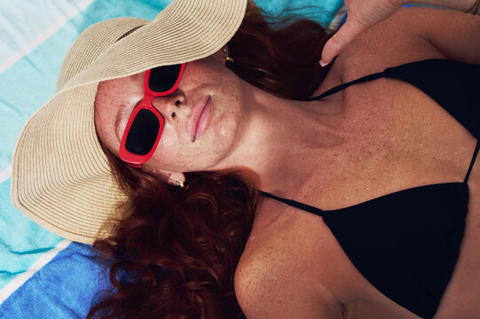 Woman relaxing poolside in sunglasses and sun hat