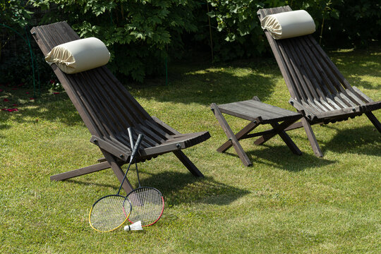 Outdoor lounge chairs and badminton set on garden lawn