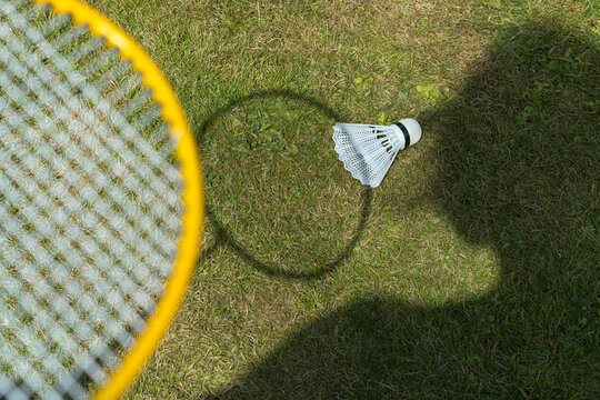 Badminton racket and shuttlecock on grass with shadow
