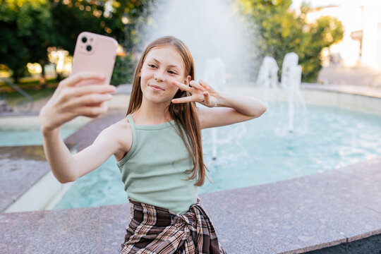 Teen girl taking selfie by fountain in city park