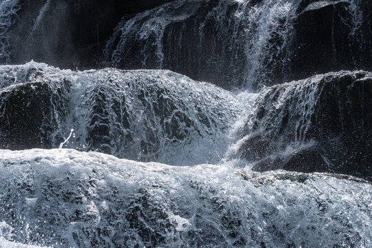 Cascading waterfall over dark rock in forest nature