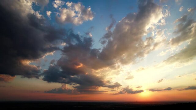Glorious rays of sunlight through colorful clouds at sunset or sunrise. A panning shot of a tranquil nature scenery with the sun and beautiful colors.