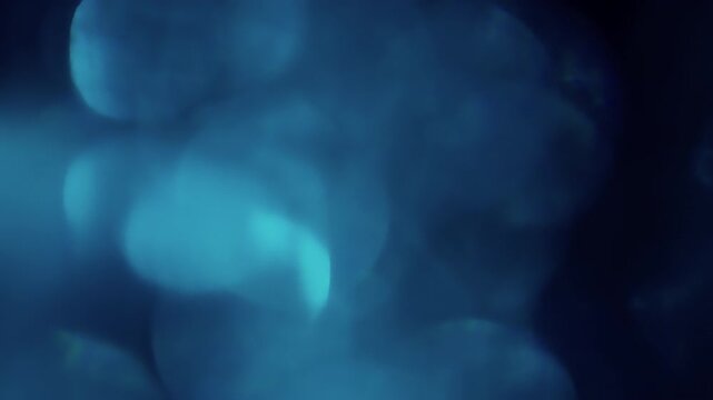 Cold blue bokeh light effects flickering as a background or overlay on a dark backdrop