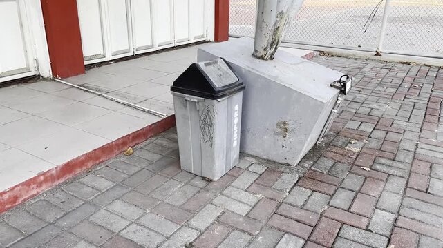 Outdoor garbage bin near concrete pillar in public park