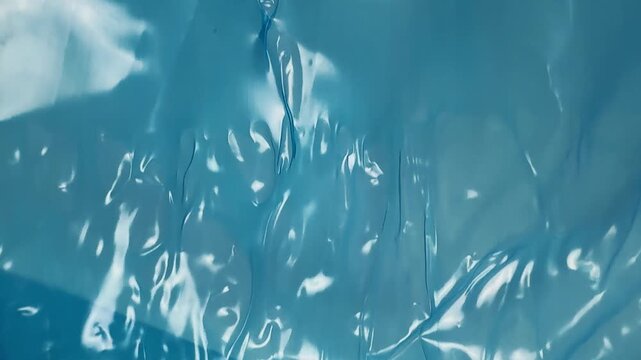 Abstract texture of blue plastic film with folds and reflections