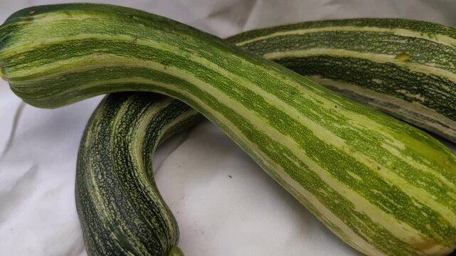 Two long striped zucchini on a white background, fresh organic vegetables, healthy cooking ingredient, farm produce, minimalist food styling.