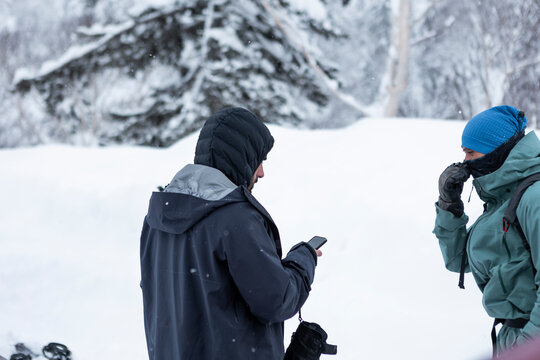 Skiers checking smartphone in snowy Hokkaido backcountry