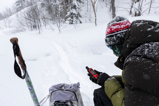 Backcountry skier checks avalanche transceiver in powder snow