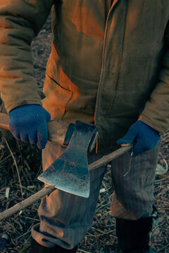 Close up of male hands in blue gloves cutting a branch with a sharp axe