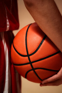 Basketball player holding an orange ball indoors
