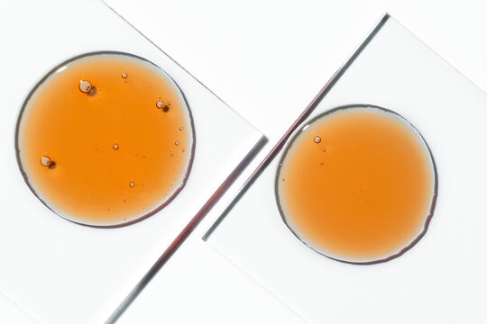 Vitamin C serum oil drop with cosmetic bubbles on glass