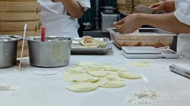 Team of chefs making dumplings inside restaurant kitchen, Chinese Dim Sum Cooking, Food Preparation, Restaurant Catering Profession, Hotel Teamwork