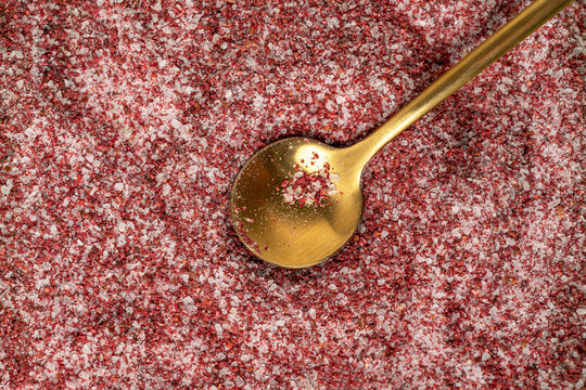 Pomegranate salt with gold spoon on textured background