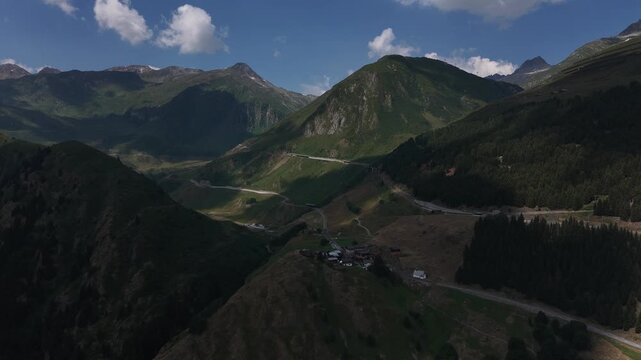 serene panoramic view of rocky mountains with lush green vegetation under a clear blue sky in a tranquil landscape, Andermatt