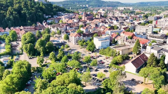 Malerische Ansicht von Homburg an der Saar mit der markanten Stadtkirche, dichten gr&uuml;nen B&auml;umen im Vordergrund und dem bewaldeten Schlossberg unter blauem Sommerhimmel.