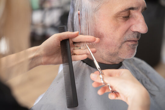 Hairdresser trim gray hair of male client at salon