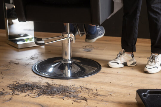 Hairdresser work at salon with cut hair on wooden floor
