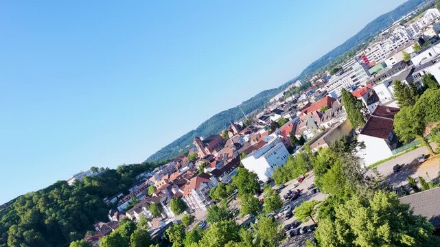 Malerische Ansicht von Homburg an der Saar mit der markanten Stadtkirche, dichten gr&uuml;nen B&auml;umen im Vordergrund und dem bewaldeten Schlossberg unter blauem Sommerhimmel.