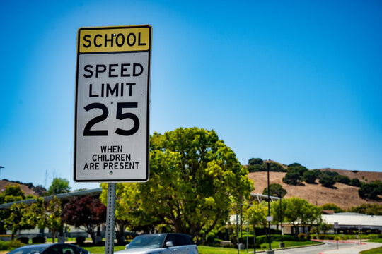 School zone speed limit 25 sign with clear blue sky and trees