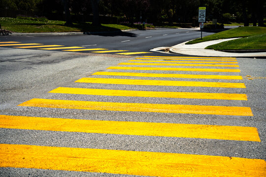 Bright yellow pedestrian crossing stripes on asphalt road surface