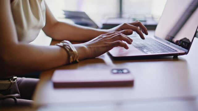 Closeup woman hands typing laptop keyboard office. Smartphone desk remote work