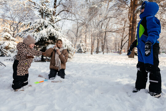 Family playing in snow as child throws powder in winter park