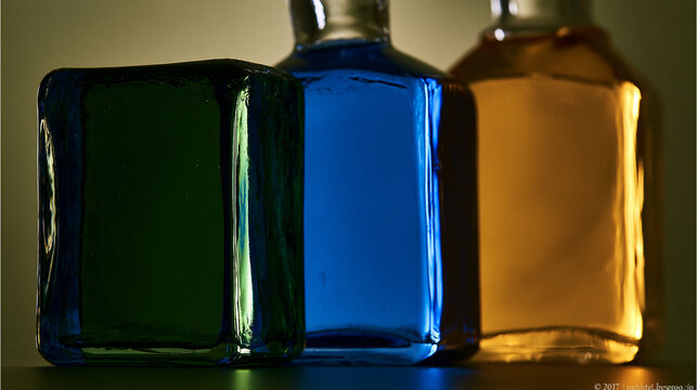 Colorful Glass Bottles with Liquids Against Light Background