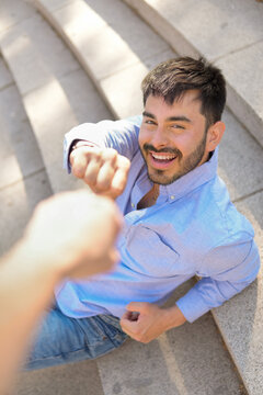 Smiling man giving a fist pound greeting outdoors