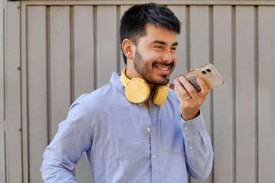 Man using smartphone voice message with headphone outdoors