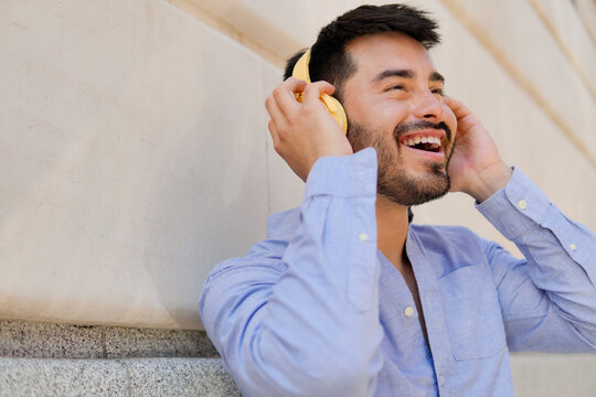 Smiling man with yellow headphones enjoying music outdoors