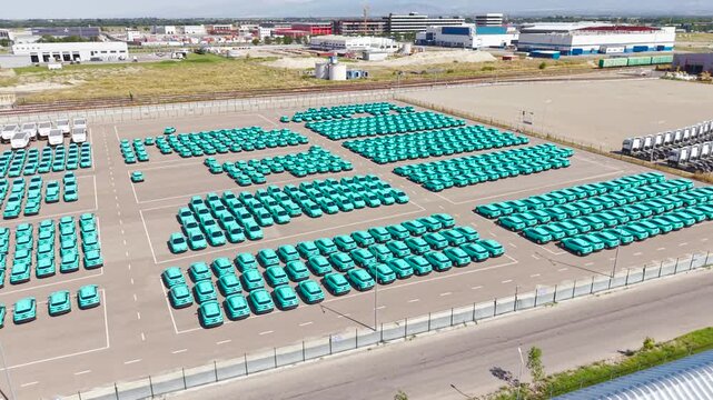 Top view of a parking lot with new turquoise electric crossover taxis.
