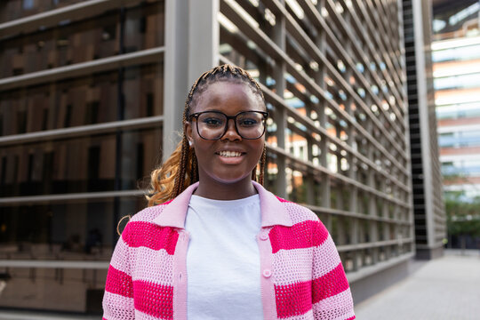 Smiling young Black woman with braids in modern city