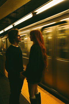 Couple on Manhattan subway platform beside passing train