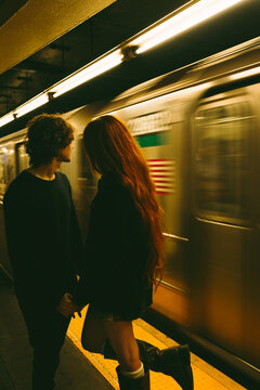 Couple waiting on Manhattan subway platform as train rushes by