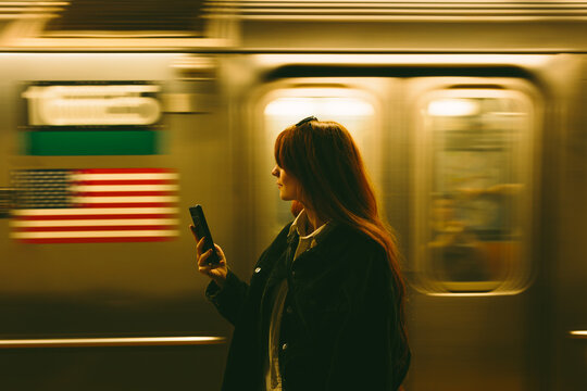 Commuter with smartphone as subway train blurs in Manhattan