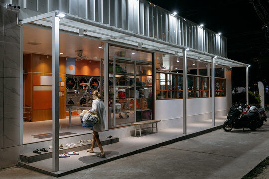 Woman entering modern laundromat at night