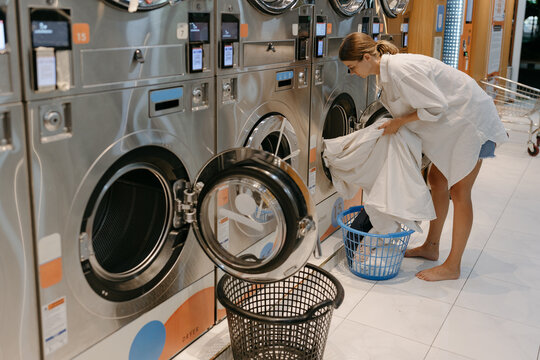 Woman using a self-service laundromat washing machine